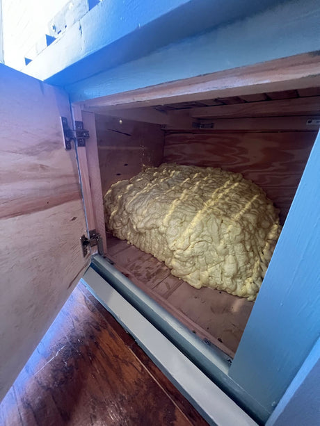 RV rental: Inside a camper's storage, light yellow spray foam insulates the wooden compartment.