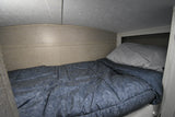 Inside an RV rental: a compact, cozy bunk bed with blue bedding and a light pillow, ideal for small spaces.
