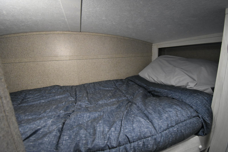 Inside an RV rental: a compact, cozy bunk bed with blue bedding and a light pillow, ideal for small spaces. — photo 15