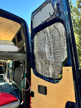 Inside this RV rental: See the cozy bed and insulated rear door of a custom van conversion, perfect for adventure.