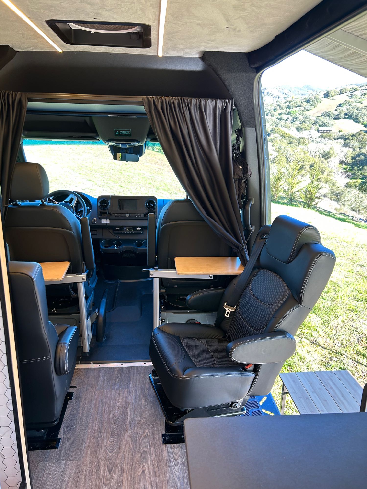 This RV rental offers a functional interior with swivel chairs, tables, and a scenic view, perfect for adventure.