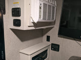 An RV rental's interior, featuring its AC unit, control panels (including solar), and TV setup.