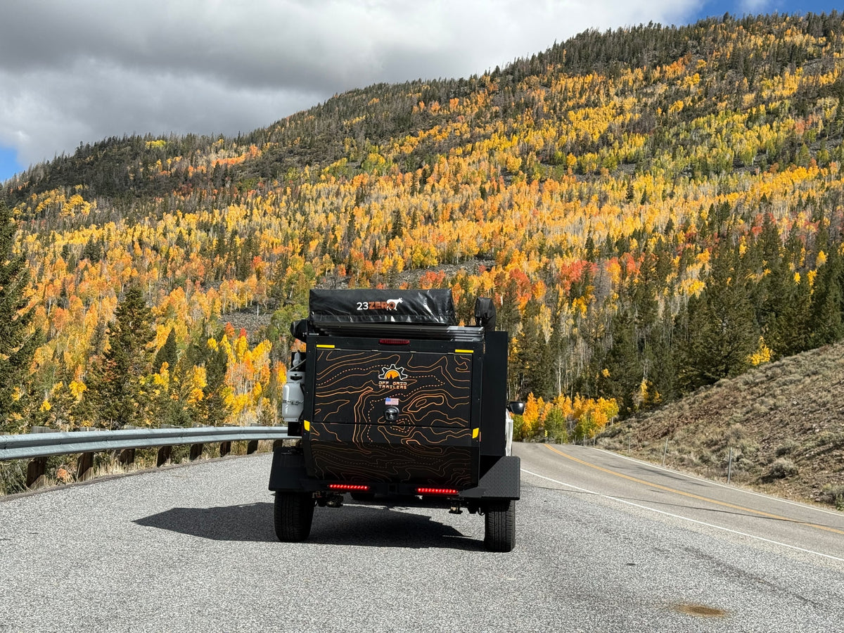  set against vibrant fall aspen trees.|An RV rental: a white pickup truck towing an off-road trailer on a mountain road with vibrant fall foliage. Camping awaits!|An RV rental off-grid trailer on a mountain road — photo 4