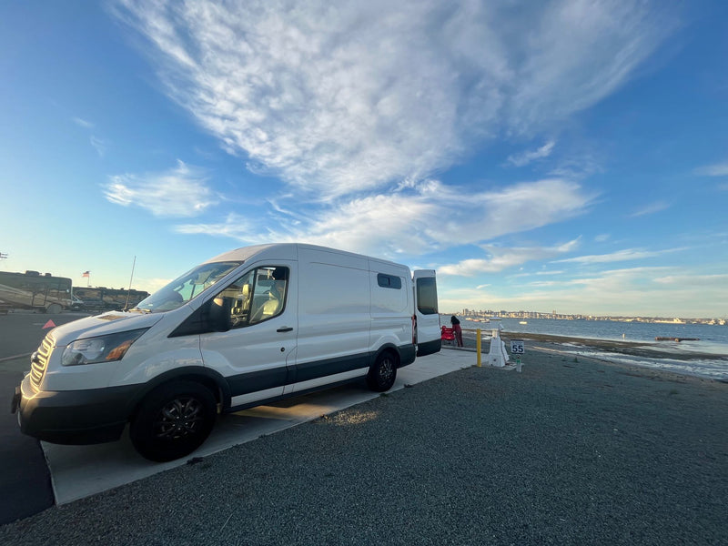  temporarily pausing its road trip.|A white rv rental van sits by a misty lake and pine forest on a rainy day. Perfect for peaceful nature exploration.|A white camper van (ideal RV rental) parked near the iconic Golden Gate Bridge at golden hour in San Francisco.|RV rental van interior showing dashboard — photo 8