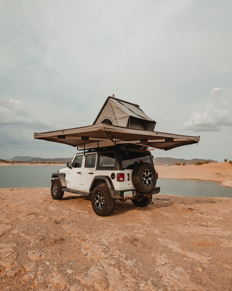 White Jeep Wrangler with rooftop tent & awning by a lake, ideal for an RV rental outdoor escape. — photo 8