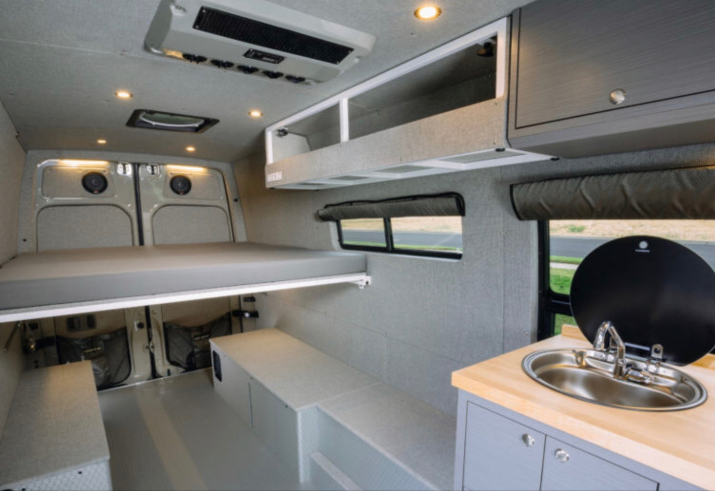 RV rental: Modern camper van interior featuring elevated bed, kitchenette, and versatile storage. — photo 6