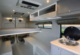 RV rental: Modern camper van interior featuring elevated bed, kitchenette, and versatile storage.