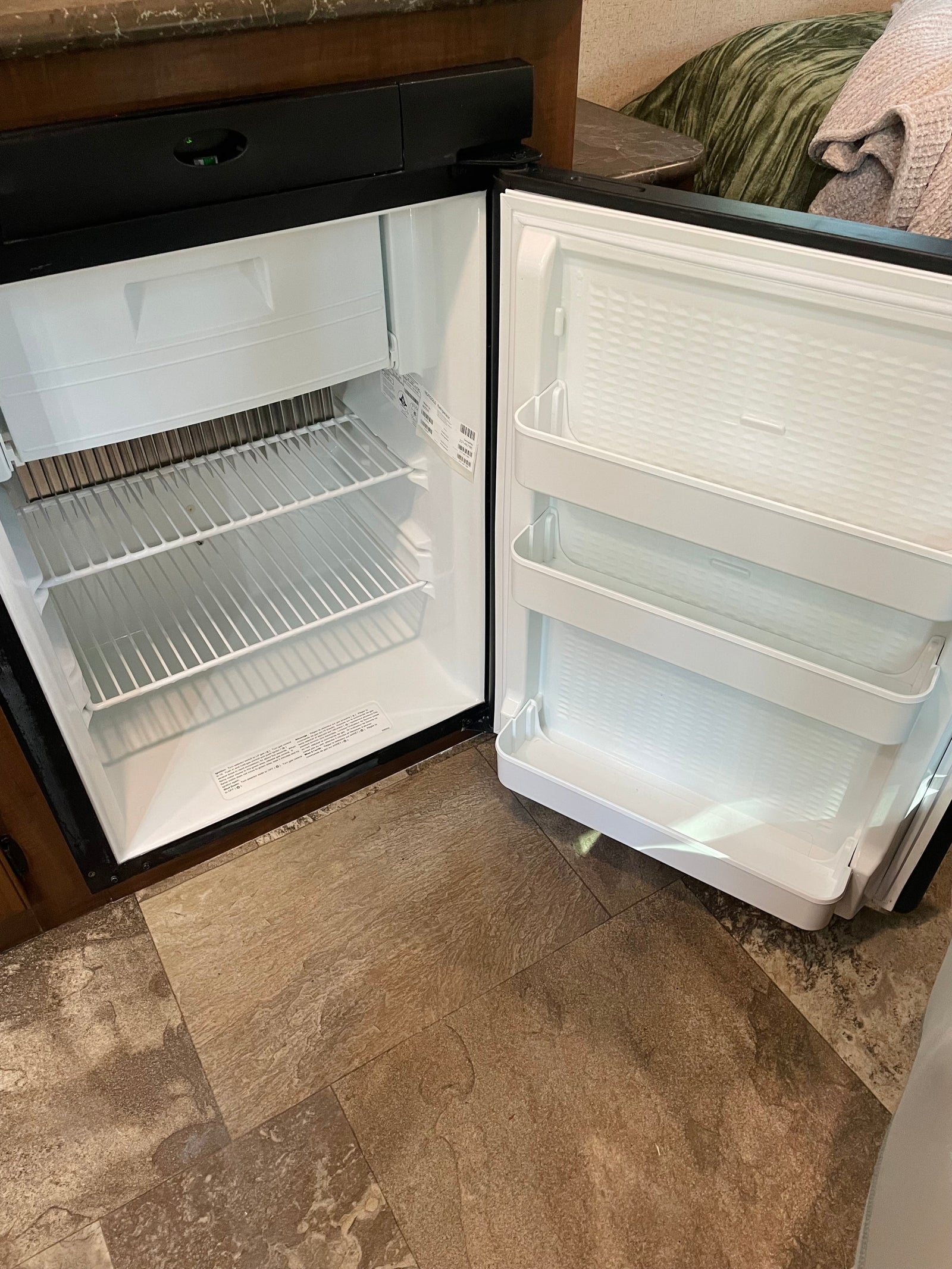 Inside an RV rental: a compact, clean refrigerator with shelves and door storage, ready for your food and drinks.