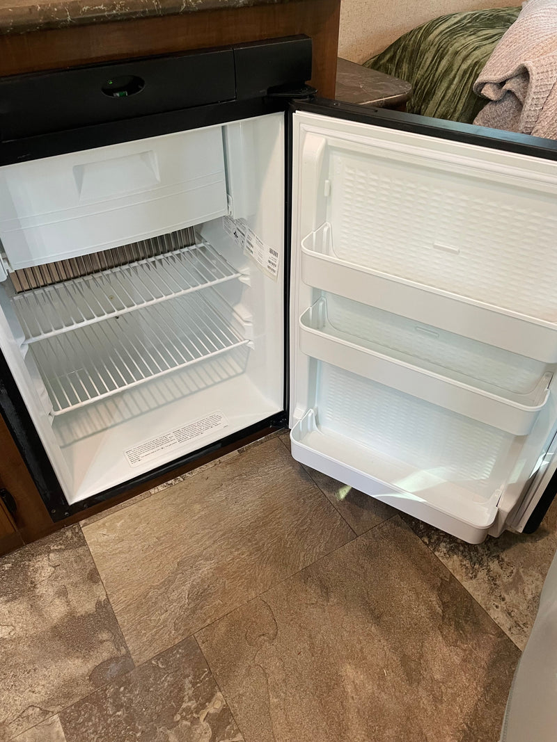 Inside an RV rental: a compact, clean refrigerator with shelves and door storage, ready for your food and drinks. — photo 11
