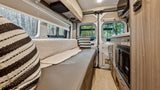 Explore the comfort of an **RV rental** with this modern camper van interior, featuring a cozy lounge and compact kitchen, amidst nature.