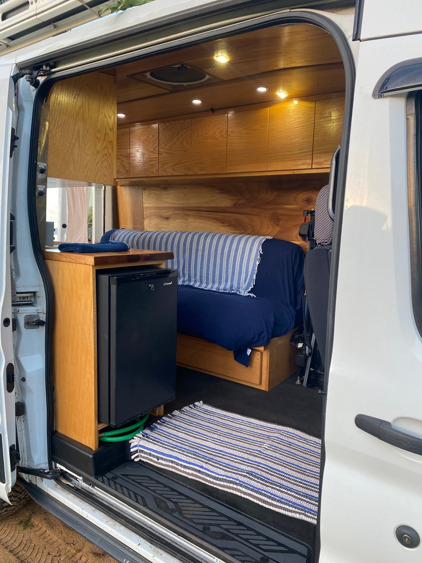 RV rental: Step inside this custom camper van, featuring a mini-fridge, wooden cabinets, and a bed.