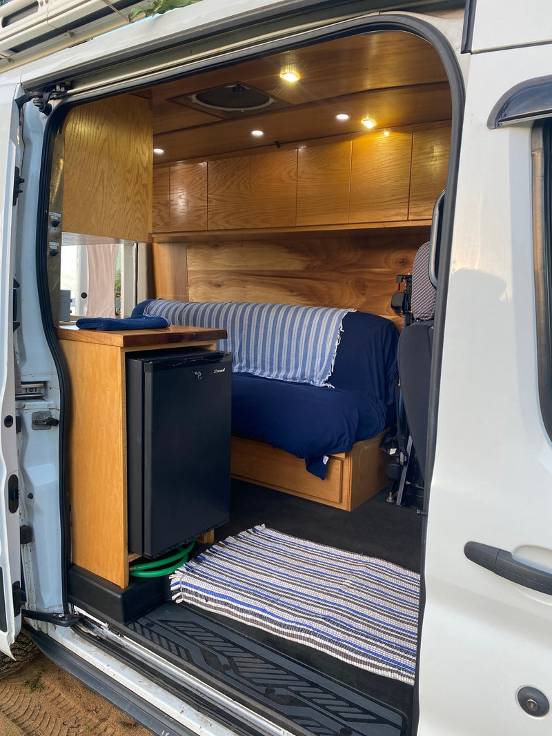 RV rental: Step inside this custom camper van, featuring a mini-fridge, wooden cabinets, and a bed. — photo 16