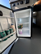 Compact mini-fridge in an RV rental, stocked with drinks and snacks for your adventure. Ideal for travel needs.