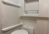 Compact white RV rental bathroom with toilet and a wall-mounted metal caddy, designed for efficient space.