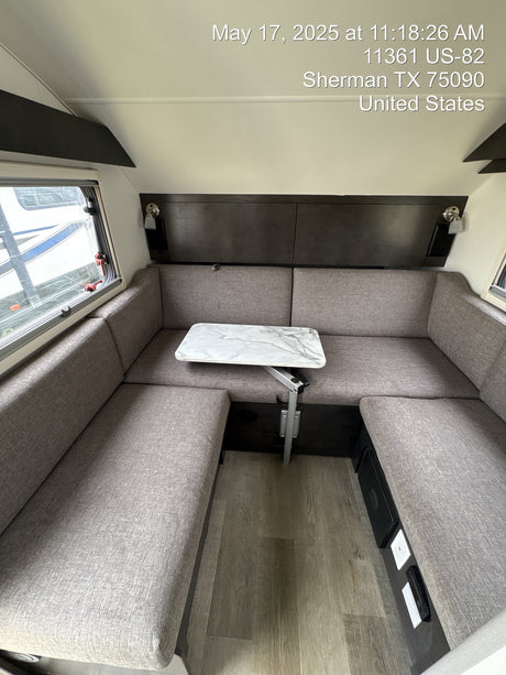Inside an RV rental, a cozy gray U-shaped dinette and adjustable marble-pattern table on wood-style flooring, Sherman, TX.