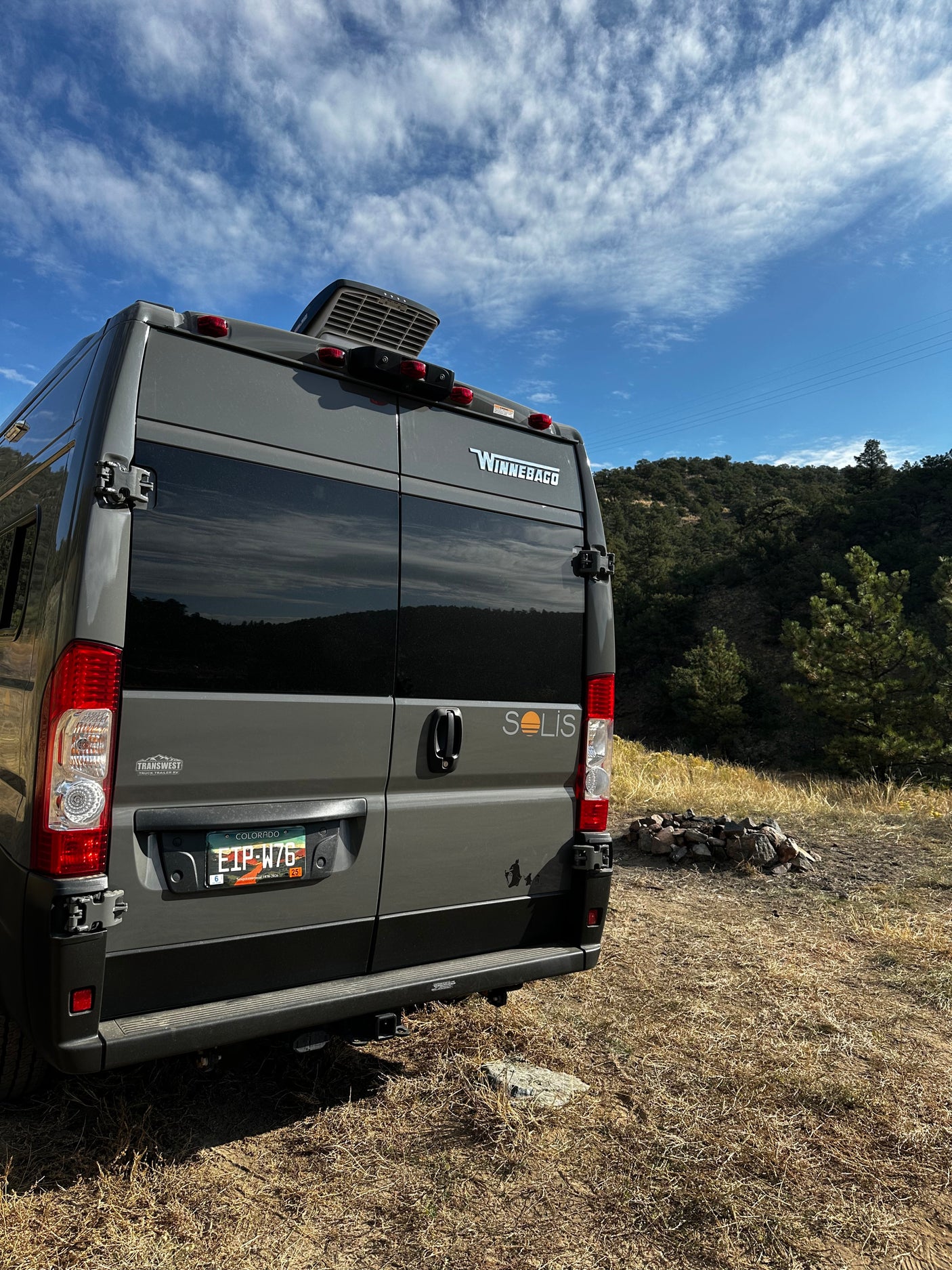 This gray Winnebago Solis rv rental is parked with a campfire pit ready for a Colorado mountain adventure.