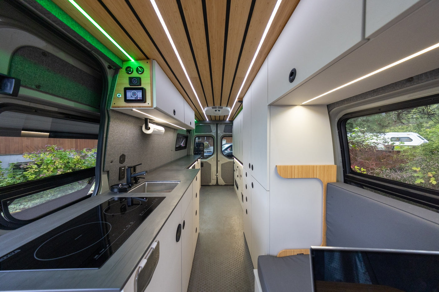 Spacious RV rental interior: A modern kitchen, slatted wood ceiling, bright LED lights, and cozy seating area.
