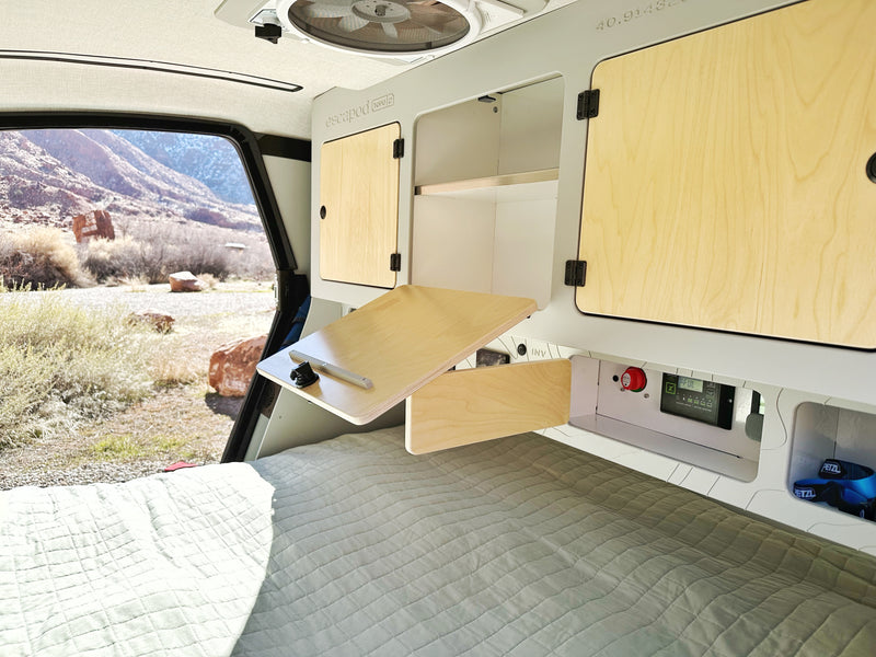Inside an Escapod RV rental: cozy bed, fold-down desk, power monitor, and stunning mountain views for your adventure. — photo 7