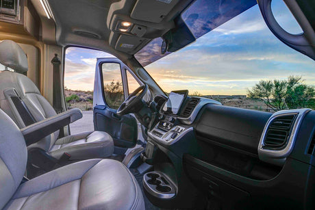RV rental camper van interior shows a modern dashboard, comfy seats, and a beautiful sunset through the windshield, ready for your road trip.