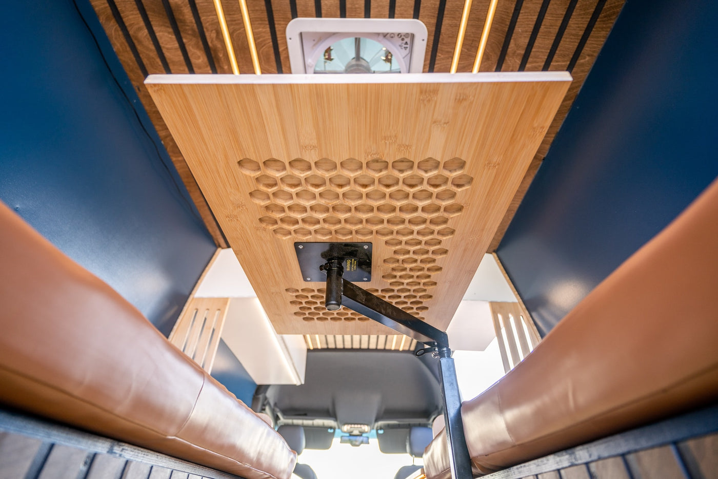 Adjustable bamboo table with honeycomb pattern and brown seating in an RV rental, featuring a ceiling fan and LED lighting. — photo 10