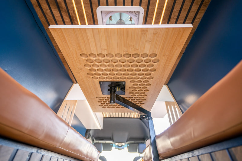 Adjustable bamboo table with honeycomb pattern and brown seating in an RV rental, featuring a ceiling fan and LED lighting. — photo 10