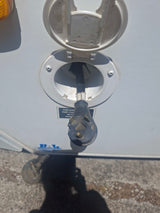 RV rental setup: A 30-amp shore power cord is plugged into the white electrical inlet on an RV.