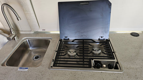 RV rental galley featuring a stainless steel sink, faucet, and a Dometic gas cooktop with an open lid.