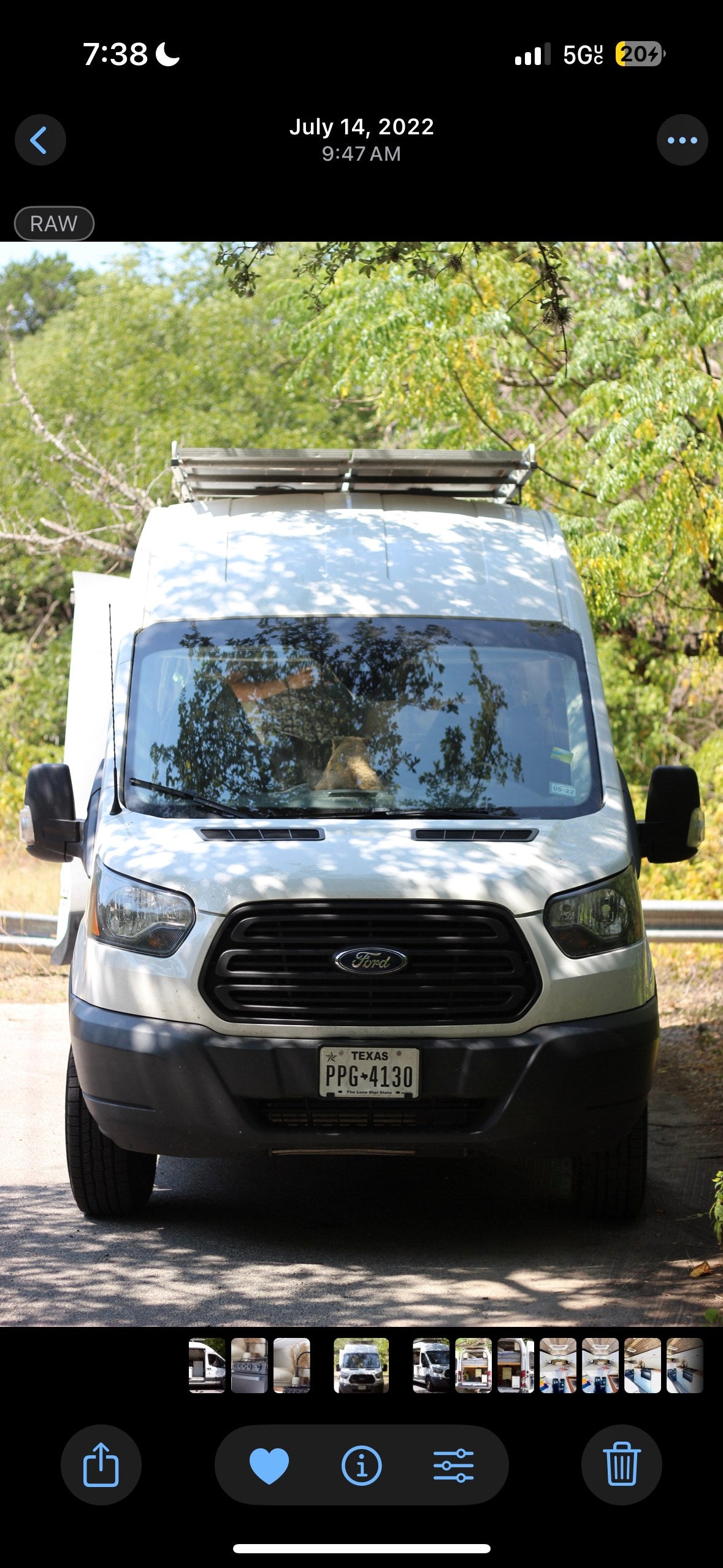 A white Ford RV rental, Texas plate PPG-4130, is parked among trees. Ideal for van life and road trips.