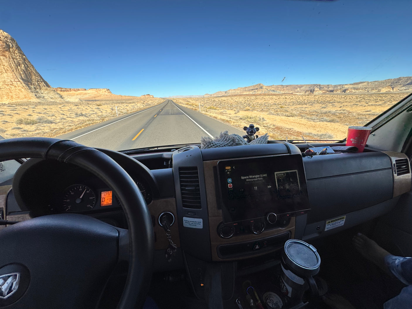 Enjoying a scenic rv rental road trip through the desert landscape, listening to Widespread Panic, with vast open roads ahead.