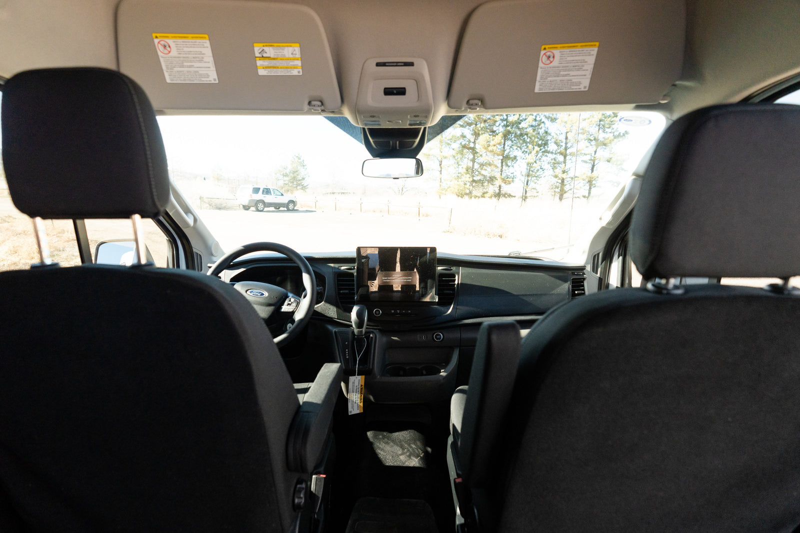 Inside a Ford RV rental van, showing the dashboard, steering wheel, and front cabin with a view of the outdoors.