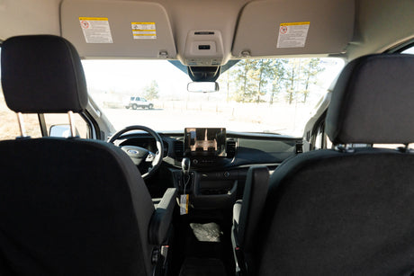 Inside a Ford RV rental van, showing the dashboard, steering wheel, and front cabin with a view of the outdoors.
