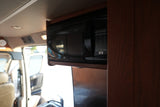Black microwave oven mounted in an rv rental, with its control panel showing options like Popcorn, Pizza, and Defrost.
