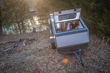 Couple enjoys a unique view from their modern RV rental with an open roof hatch, overlooking a tranquil lake.