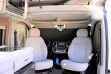 RV rental interior: Front cabin with white captain's chairs, dashboard, and integrated kitchen with microwave.