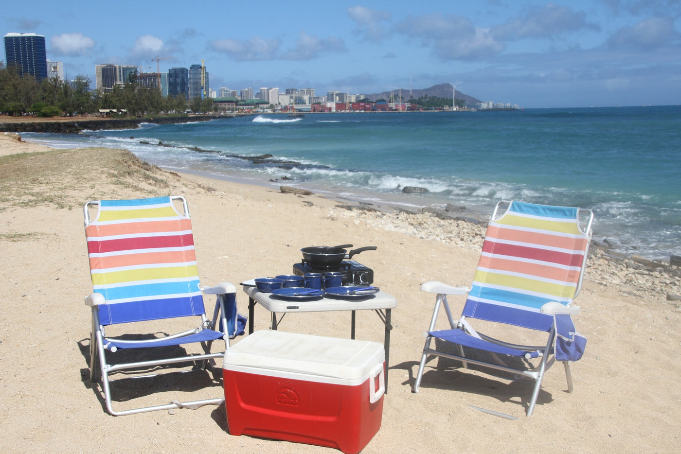 Enjoy a Hawaiian beach picnic from your RV rental! Setup includes vibrant chairs, cooler, and camp stove by the ocean. — photo 14