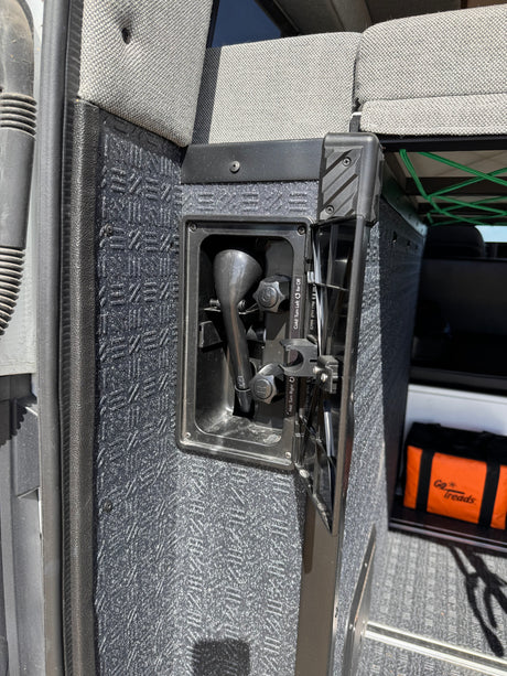 Inside an RV rental, a built-in outdoor shower with hot/cold controls and a textured panel is ready for utility.