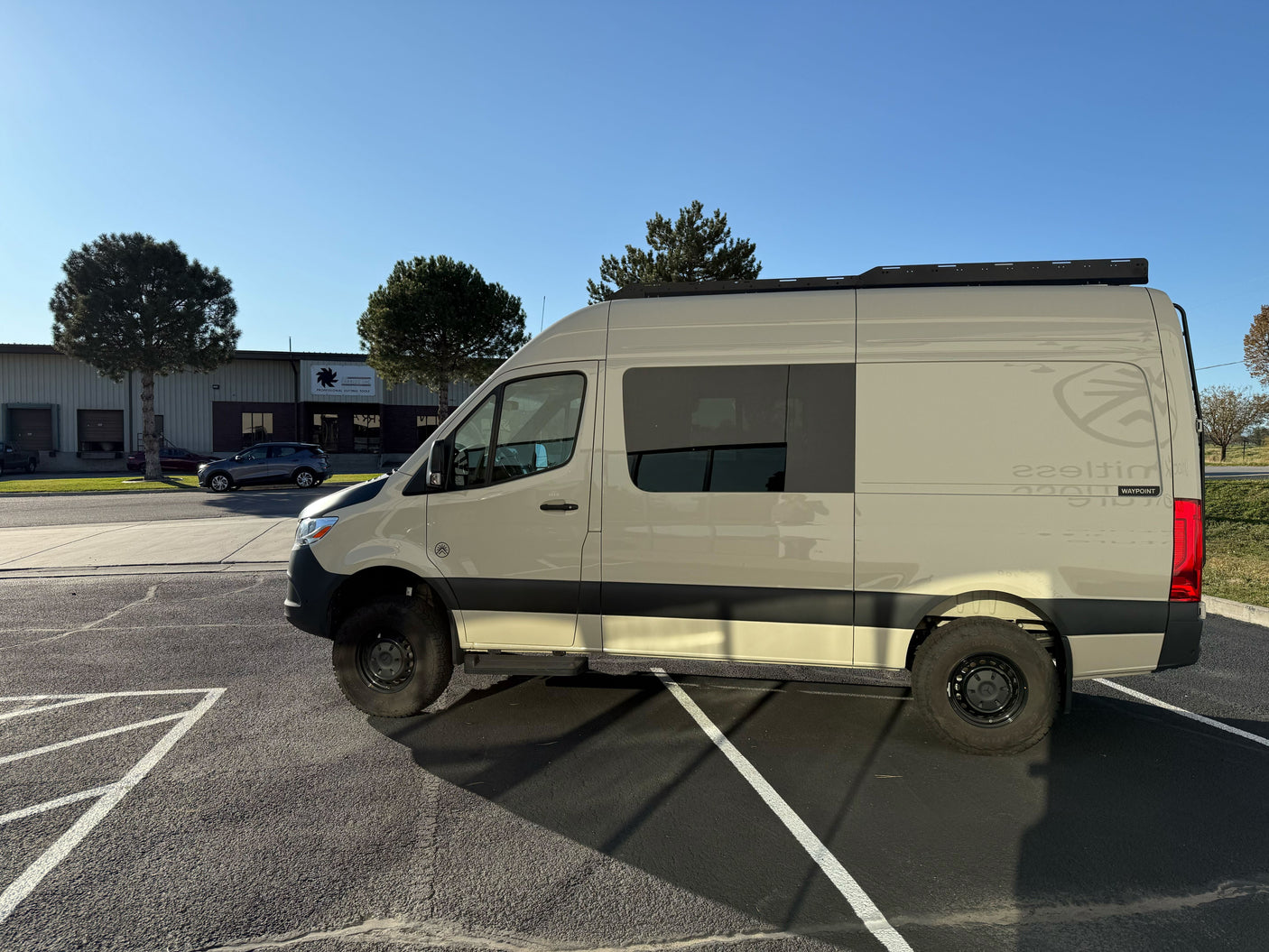 Explore with this tan Mercedes Sprinter adventure van, perfect for RV rental. Parked outside a building on a sunny day.
