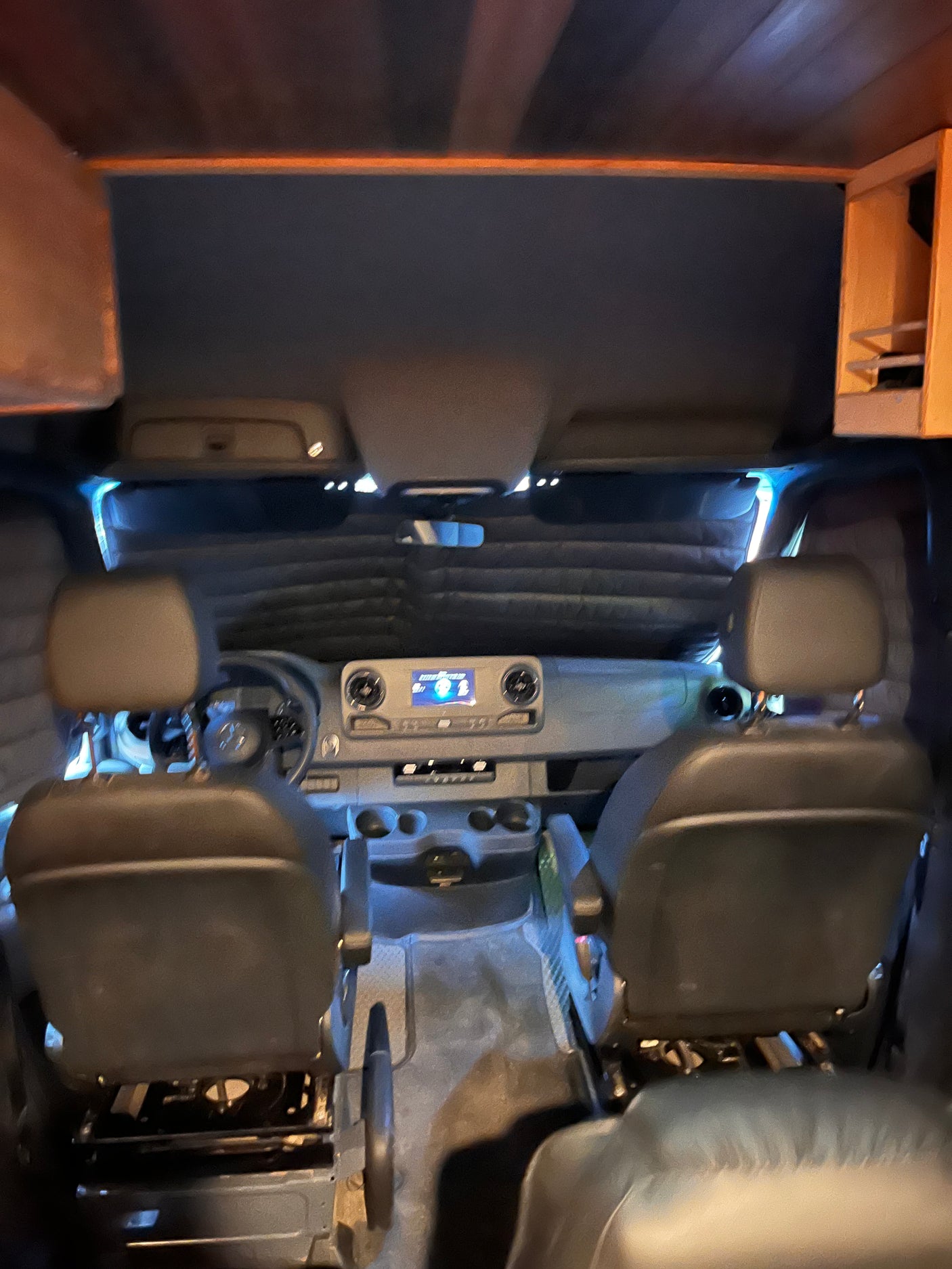 Inside a spacious RV rental, featuring passenger seating, a control console, and subtle ambient lighting for road trips.