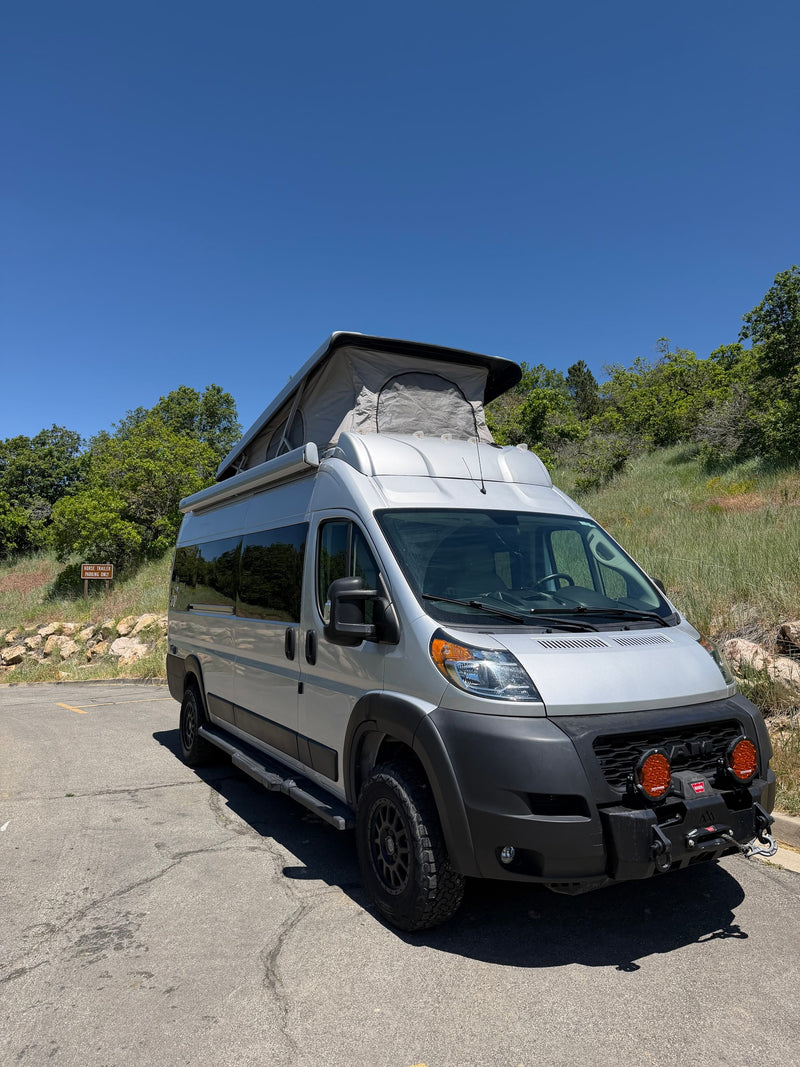 Silver pop-top camper van RV rental, with off-road tires & winch, parked in a scenic natural area on a sunny day. — photo 2