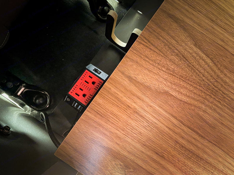 Powering your devices in an RV rental: This image shows a red power inverter with AC outlets and USB ports, integrated beside a wooden tabletop. — photo 9