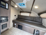 An RV rental interior showcasing a bench seat, solar control panel, audio system, and ceiling fan.