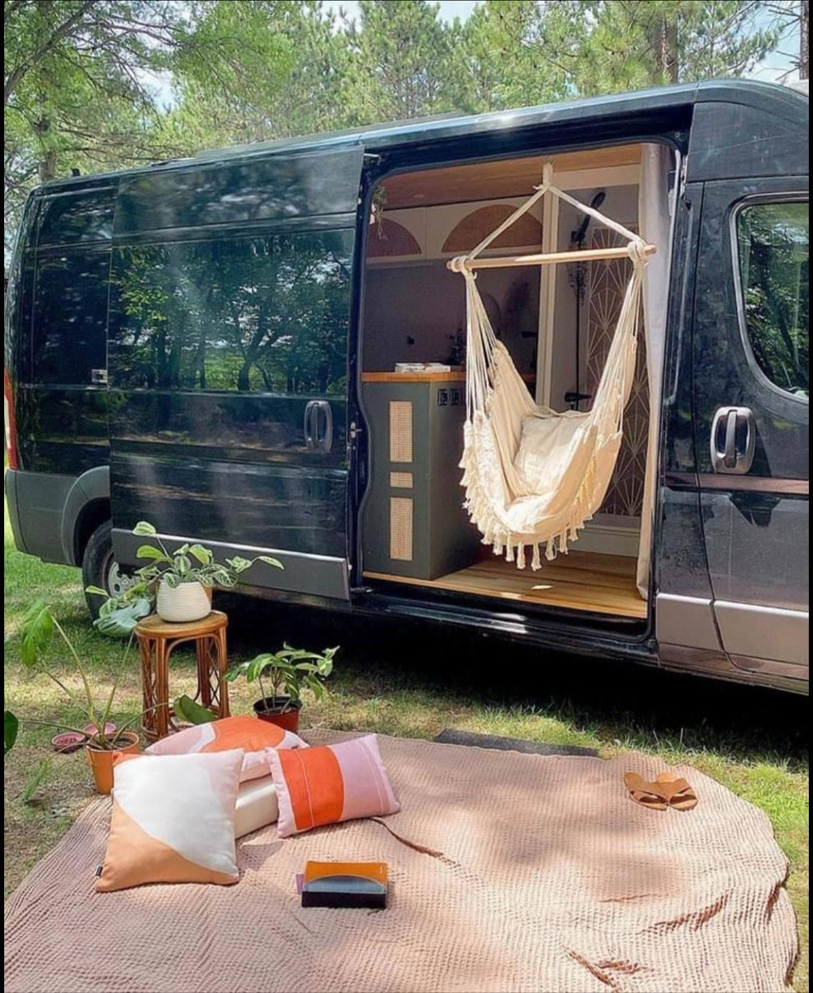 RV rental: Black camper van with open door, featuring a hanging chair & cozy outdoor picnic setup on grass. Perfect for nature escapes. — photo 7