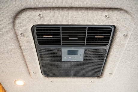 A Dometic RV air conditioner with adjustable vents and digital controls mounted on a textured ceiling, common in an rv rental.