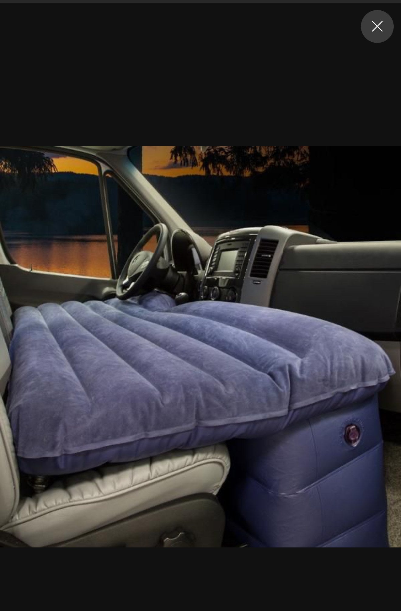 Plush purple inflatable mattress in an RV rental van's front cabin, creating a cozy sleeping area over the seats.