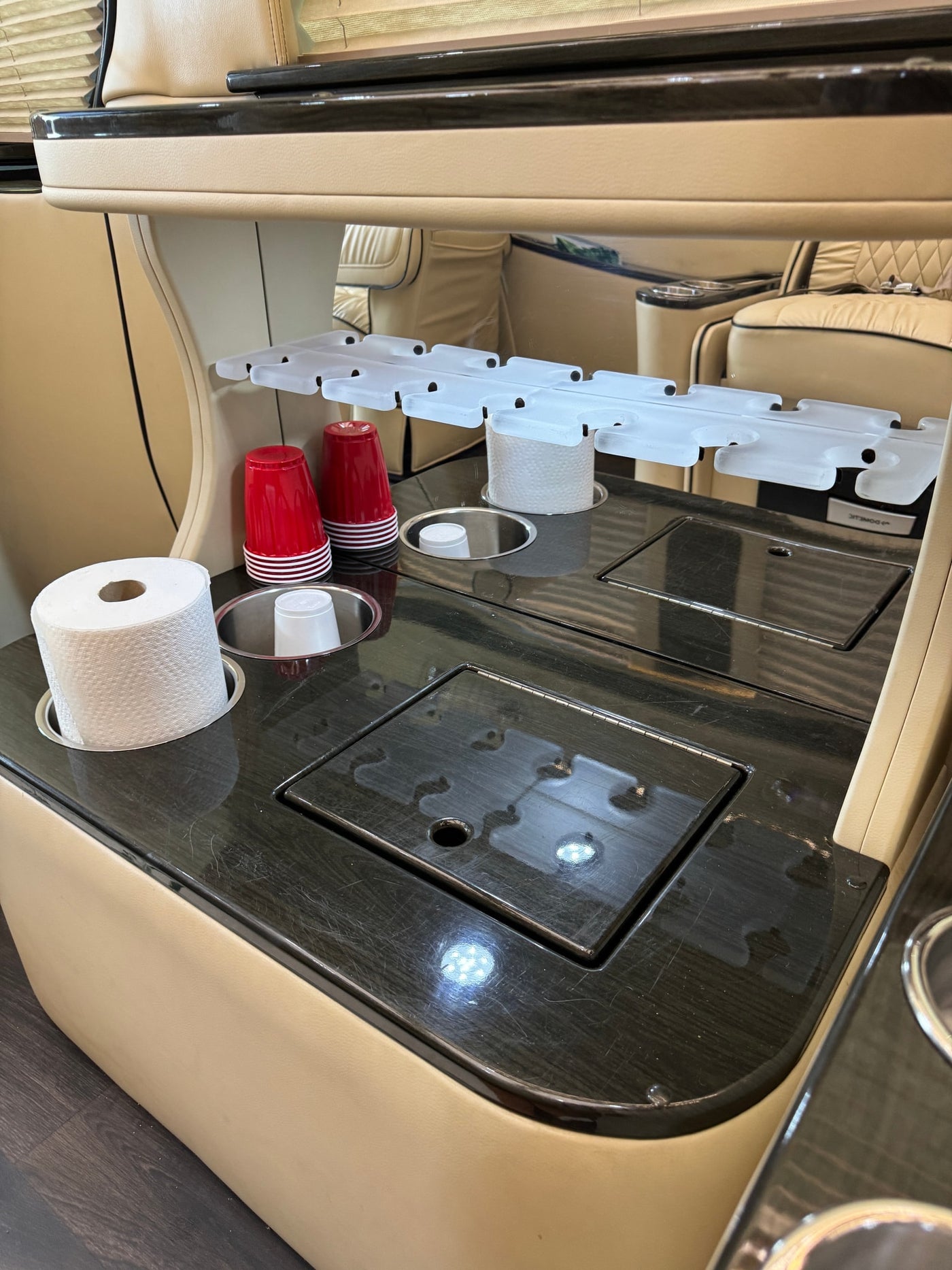 RV rental interior showcasing a dark wood counter with cup holders, paper towels, and covered storage compartments. — photo 8