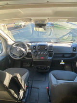 RV rental interior: detailed dashboard, steering wheel, and front seats from a passenger's perspective.