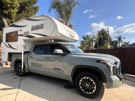 A grey Toyota Tundra pickup truck with a white Lance truck camper, ideal for your next RV rental adventure.