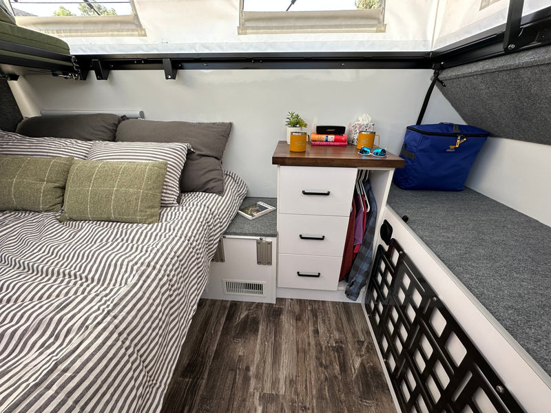 Cozy RV rental bedroom with striped bed, practical nightstand, and smart storage bench for a comfortable travel experience. — photo 4