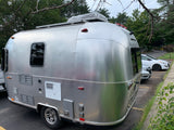 A sleek, silver Airstream travel trailer with a Dometic AC unit on top, seen here, often rented as an RV rental.