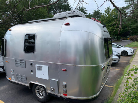 A sleek, silver Airstream travel trailer with a Dometic AC unit on top, seen here, often rented as an RV rental.